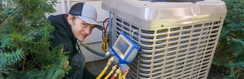 An HVAC technician works on a heat pump