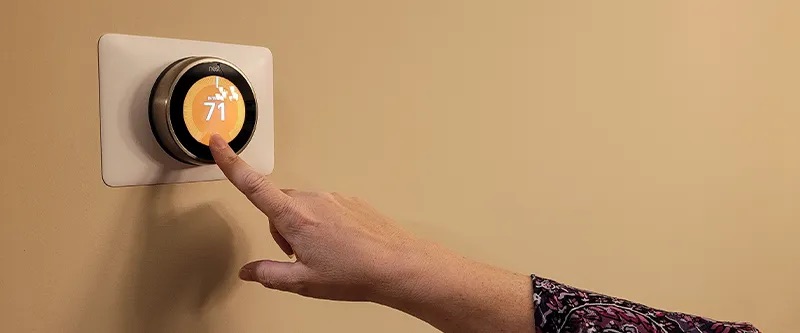 Woman interacting with a Nest smart thermostat