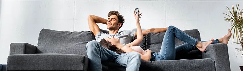 A comfortable woman and man lay relaxed on a couch