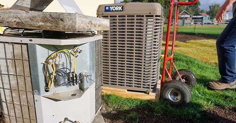 A new York air conditioner on a hand truck next to an old AC that is about to be replaced